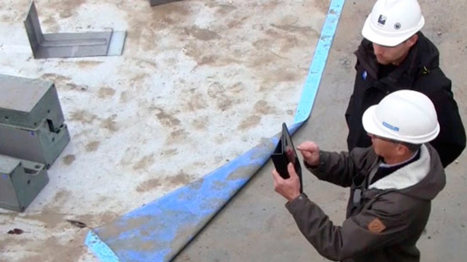 To mænd der arbejder på en byggeplads og bruger en iPad.