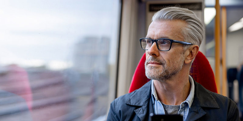 Mand i tog med mobilen i hånden