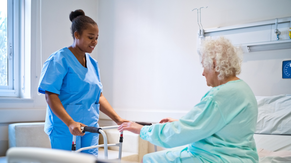 Plejepersonale hjælper ældre kvinde, der er gangbesværet