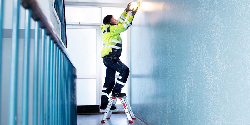 a janitor fixing a light fixture