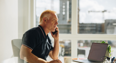 En senior der taler i telefon på sit kontor