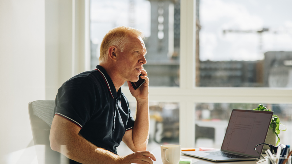 En senior der taler i telefon på sit kontor