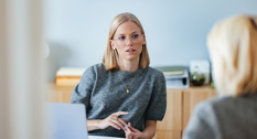 Kvinde sidder ved bord og taler med sin leder