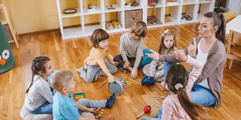 Pædagog og børn bruger instrumenter i en daginstitution.