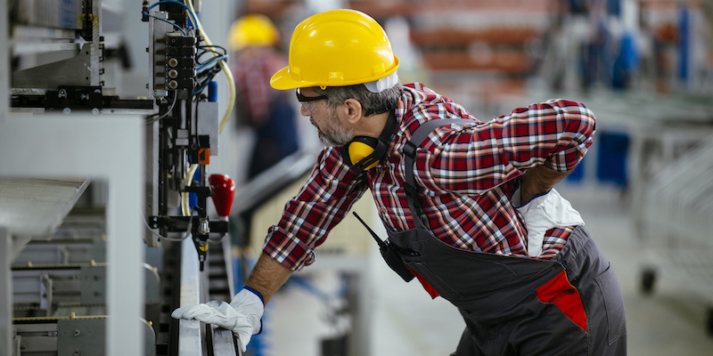 En fabriksarbejder tager sig til ryggen
