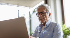 Senior sidder ved computer og arbejder