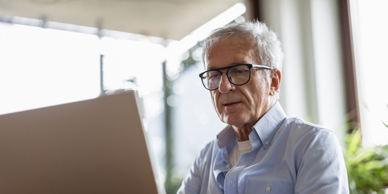 Senior sidder ved computer og arbejder