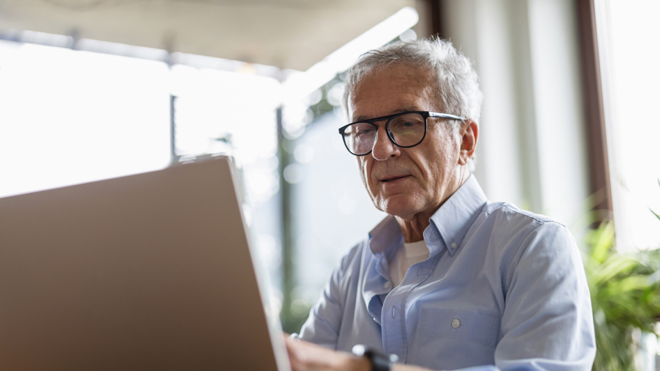 Senior sidder ved computer og arbejder