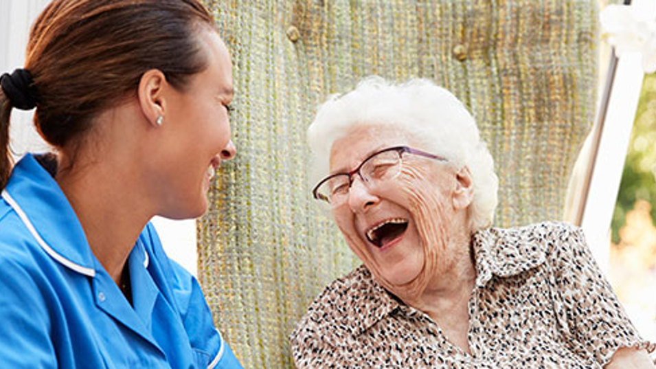 En plejer der griner sammen med en ældre kvinde