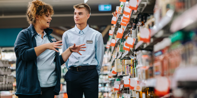 Leder og medarbejder i dagligvarebutik taler sammen om arbejdet.