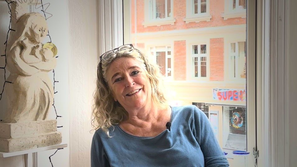 Gitte sidder i sin stue og smiler