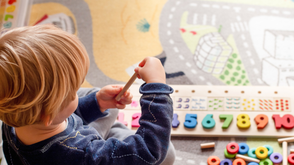 Et barn der sidder og leger med noget legetøj i sin institution