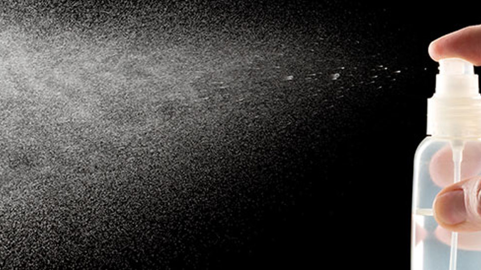 En hånd der sprayer noget væske ud af en flaske