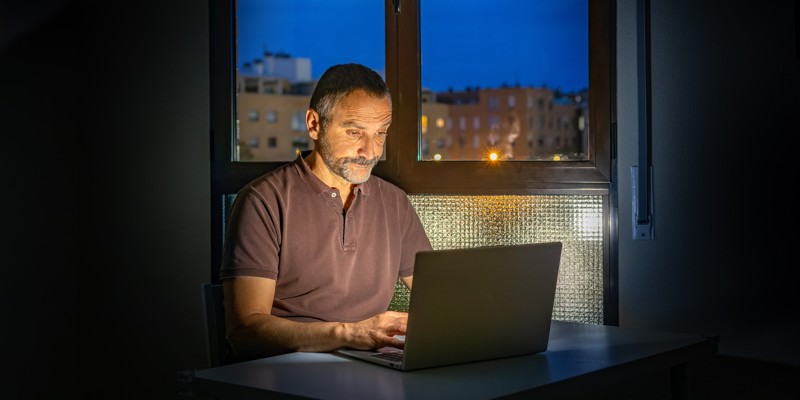 En seniormedarbejder der arbejder hjemmefra om aftenen