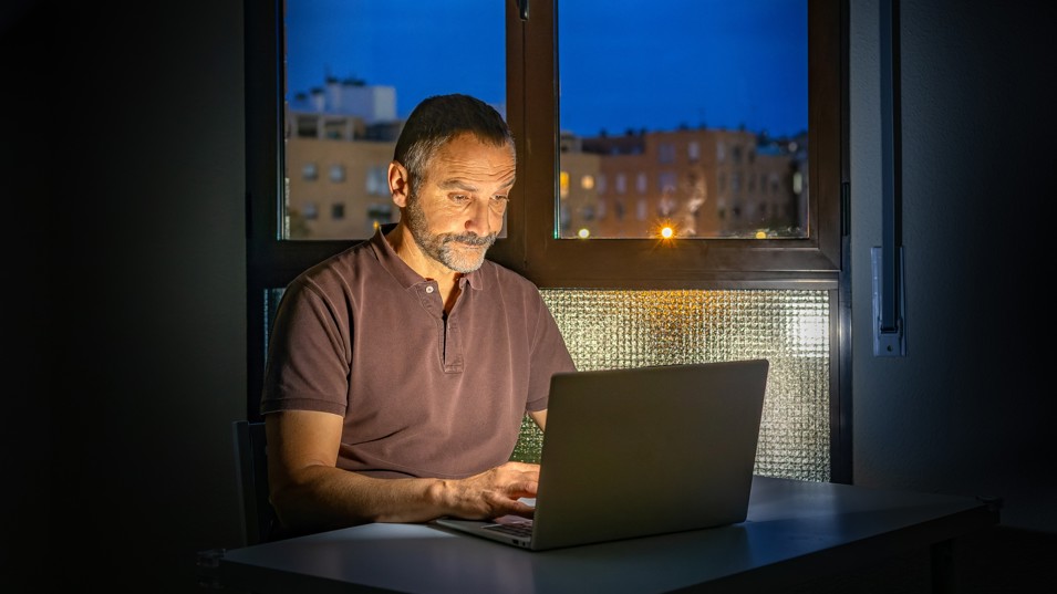 En seniormedarbejder der arbejder hjemmefra om aftenen