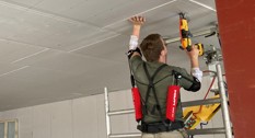 Tømrer iført skulder-exoskelet under loftmontering